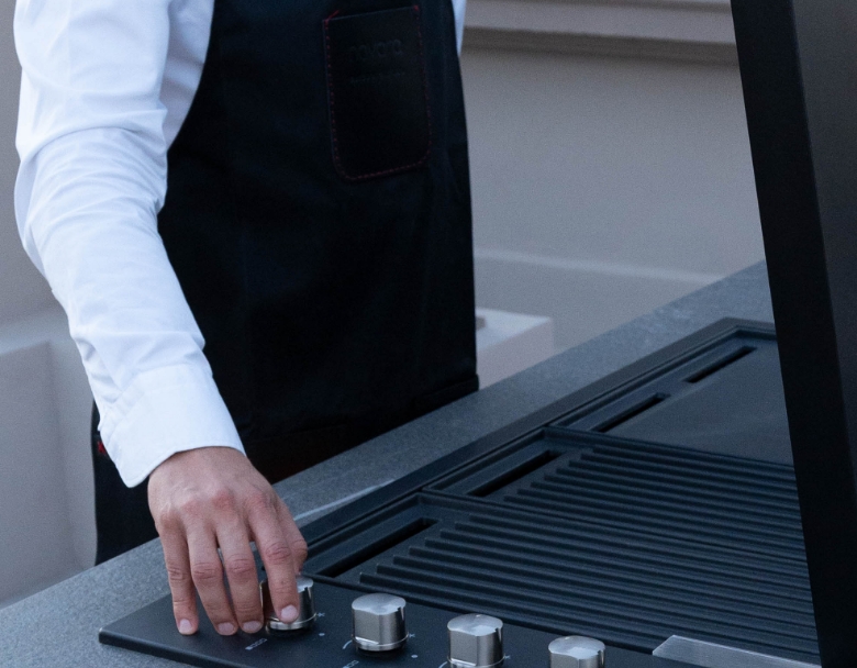 CHEF QUI UTILISE LE GRILL SUR UNE CUISINE D’EXTÉRIEUR